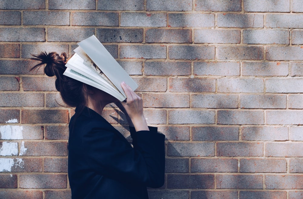 woman covering her face with white book