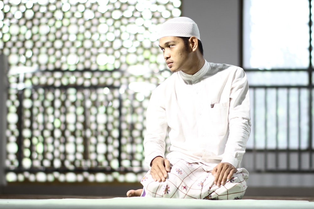 man in white thawb kneeling on floor