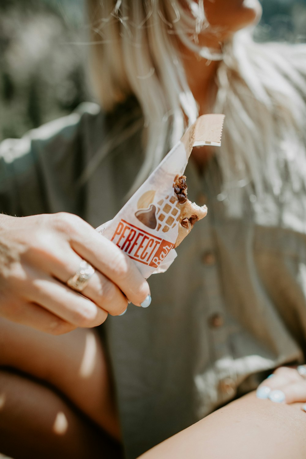 person sitting and holding Perfect Bar chocolate with bite