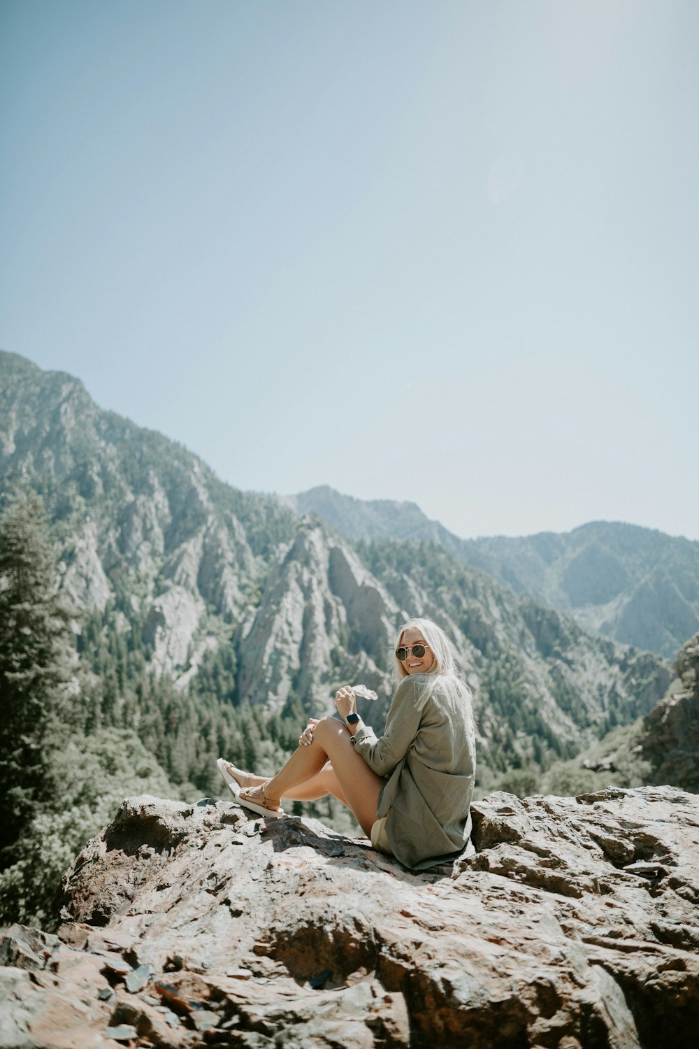 Donna che indossa una camicetta grigia che si siede sulla roccia durante il giorno
