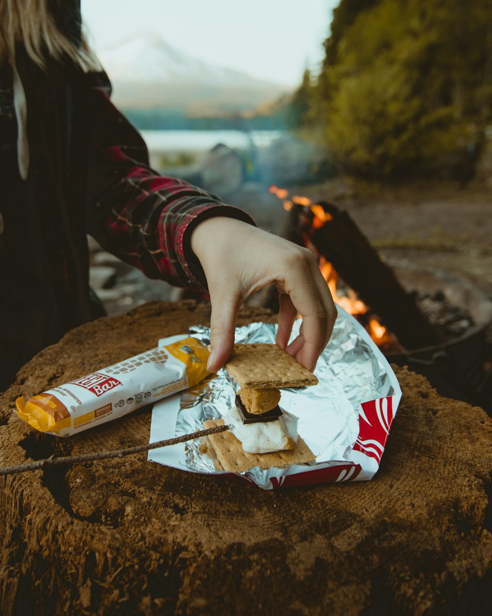 person making a biscuit sandwich near bonfire