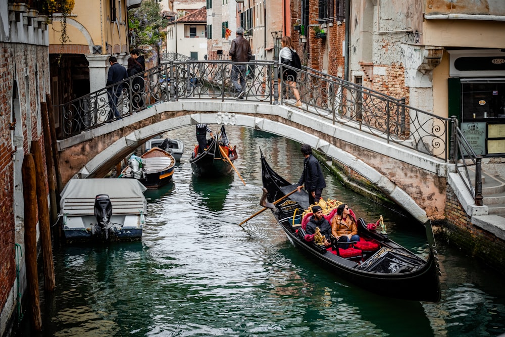 people riding boat near bridge with people crossing during daytime