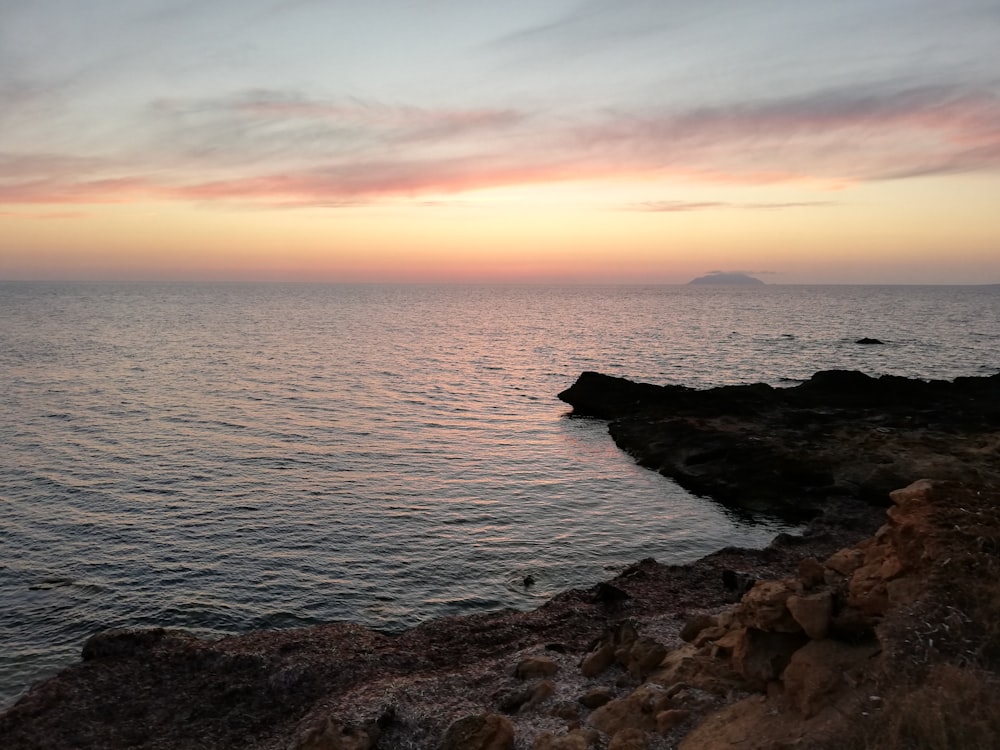 seashore near rock formation during golden hour