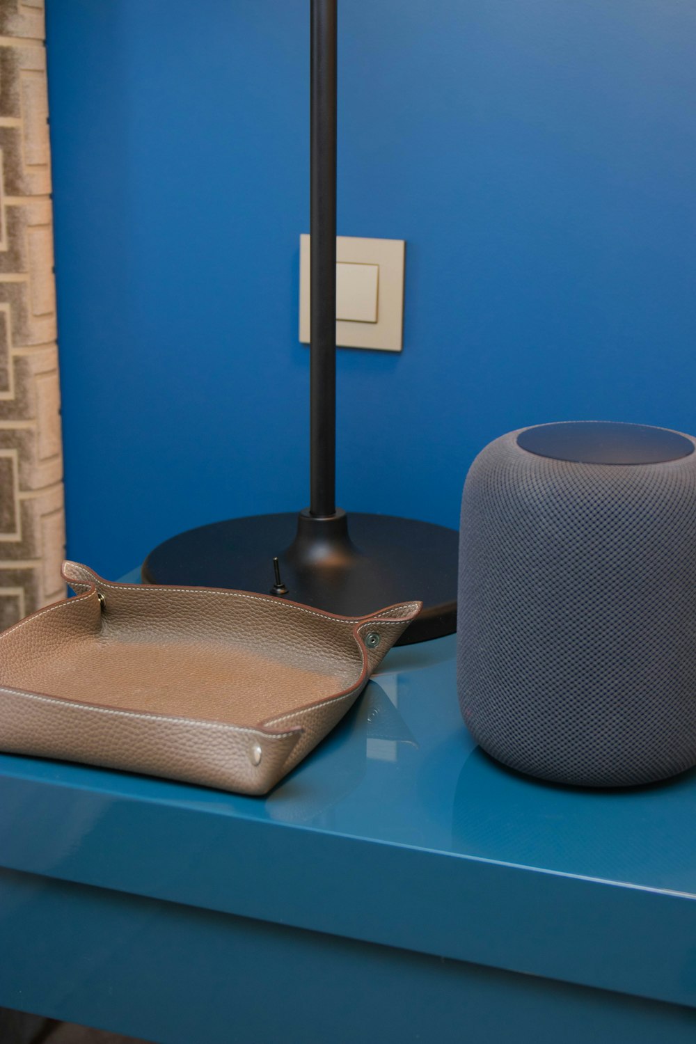 brown leather tray beside gray portable speaker and black table lamp base