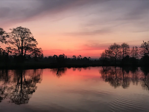 Calm waters reflecting the vibrant colors of a sunset sky over a quiet lakeside retreat.