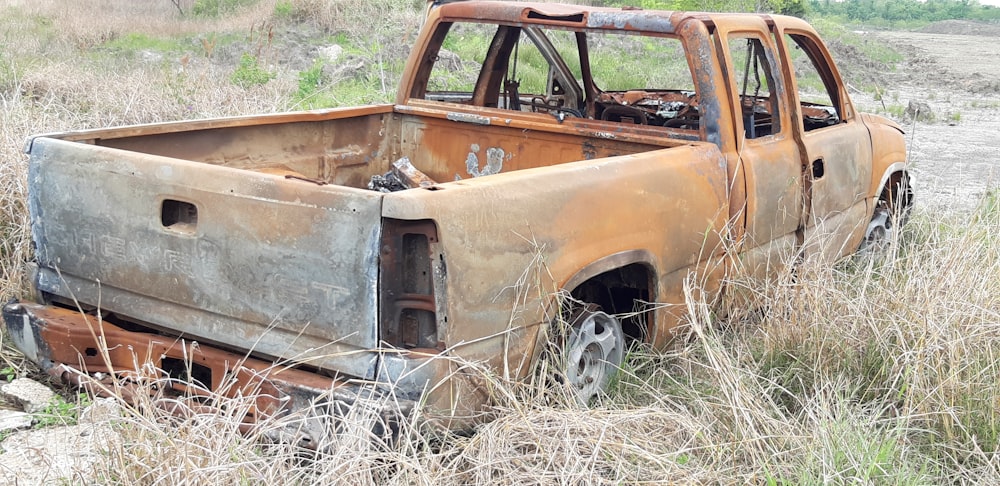Camioneta pickup marrón abandonada con cabina extra en la hierba durante el día