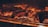 Several pieces of meat are being grilled over an open flame. The surface of the meat is charred, indicating high heat and searing. The glowing embers and fiery orange hue create a warm atmosphere.