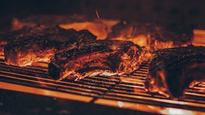A rustic grill with glowing embers and sizzling alpaca meat over open flames.