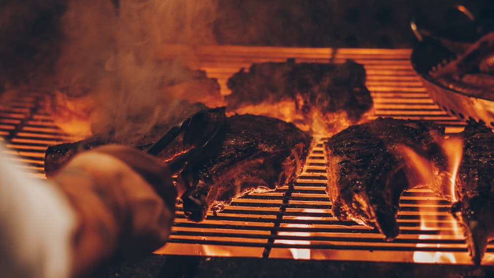 Foto de primer plano de la persona asando carne a la parrilla