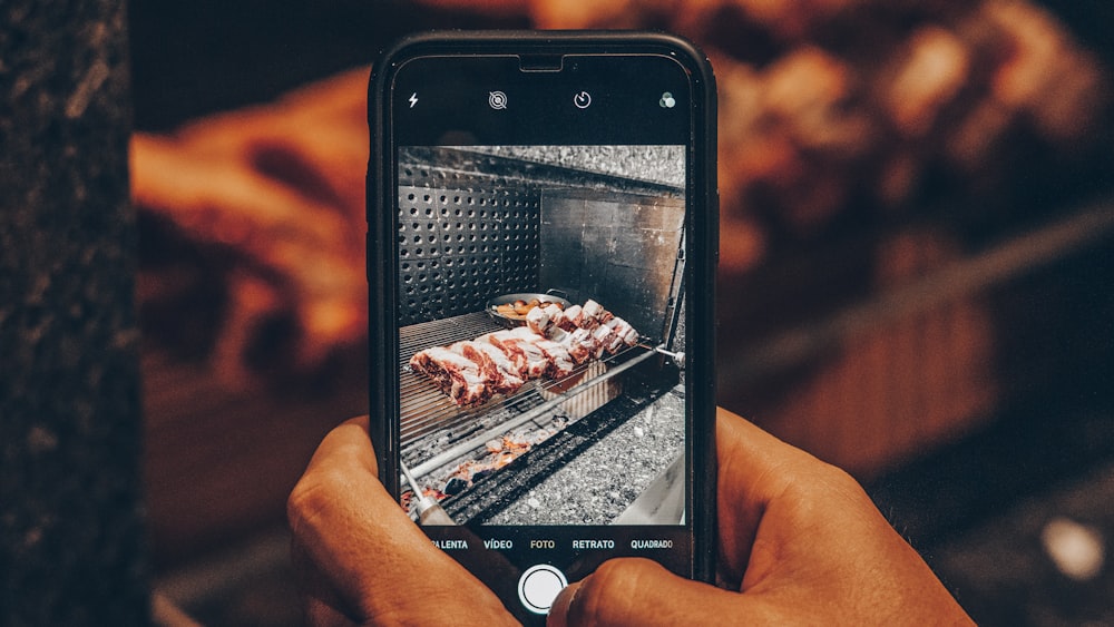 person showing photo o grilled meat on phone