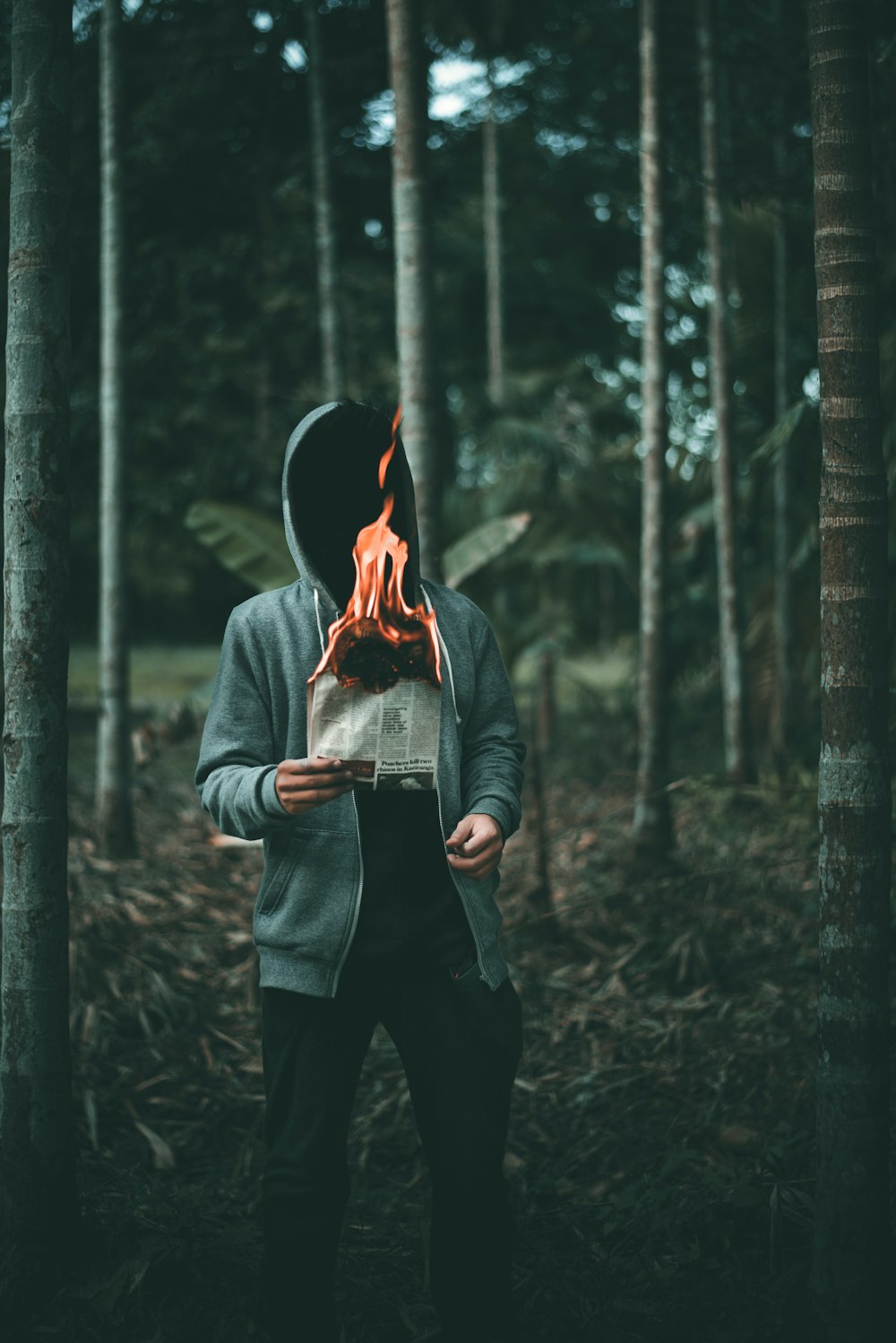나무 근처에서 불타는 종이를 들고 있는 남자