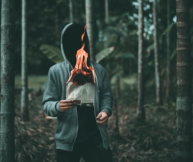 man holding burning paper near trees