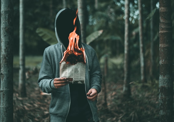 man holding burning paper near trees