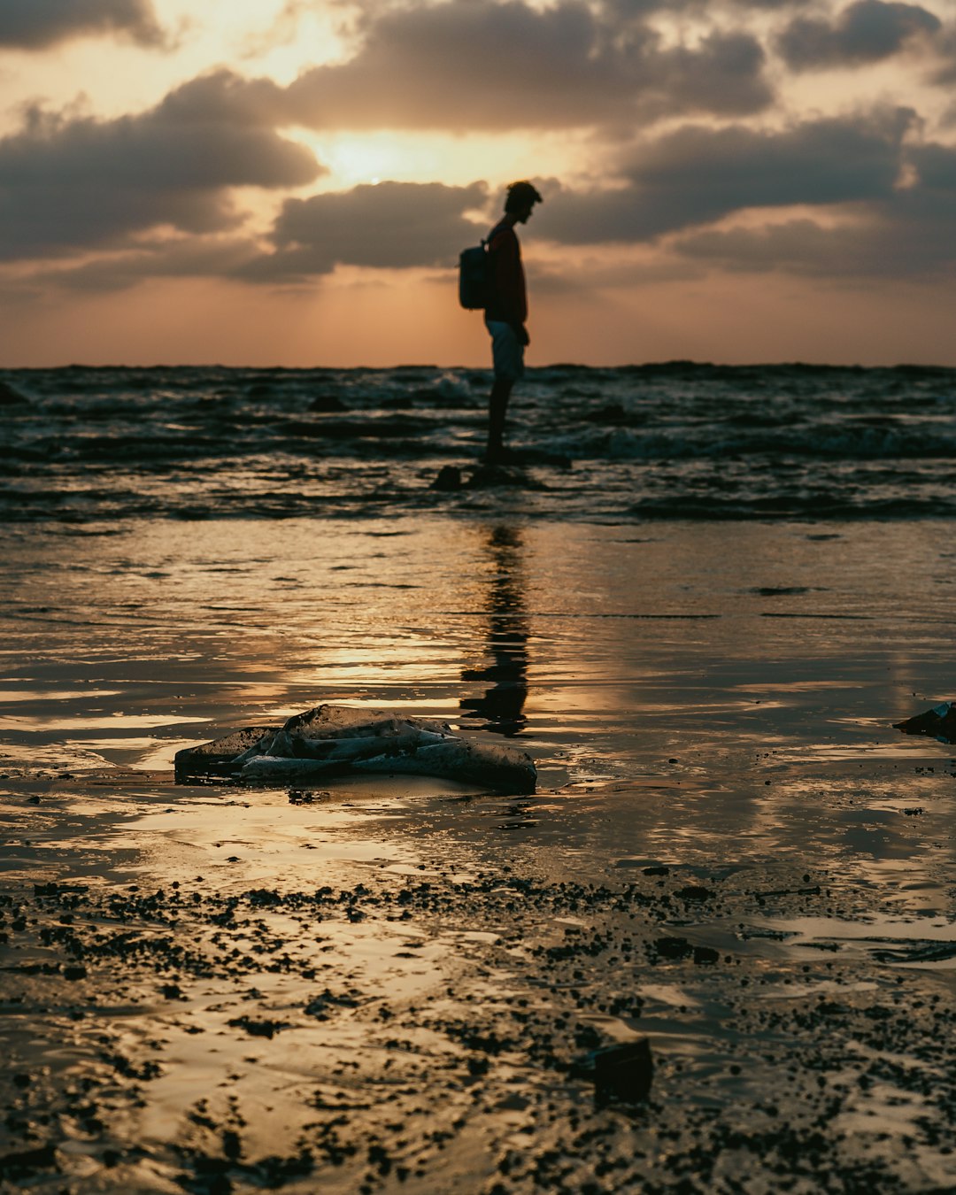 man standing on stone at the beach