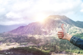 human showing hand on top of mountain