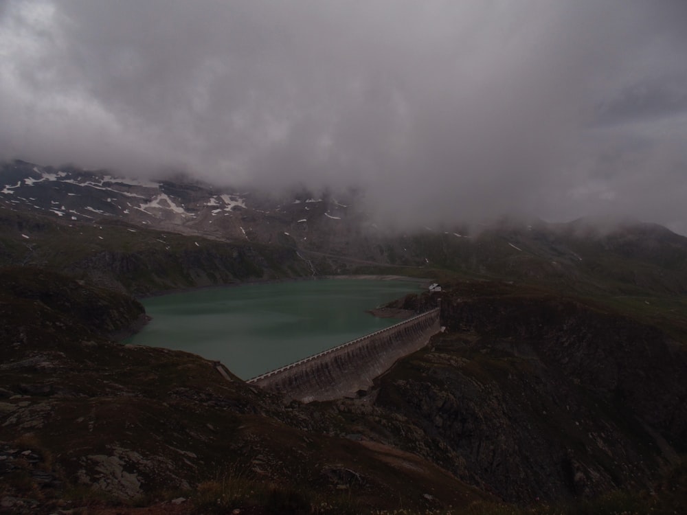 body of water with dam in the mountains during day