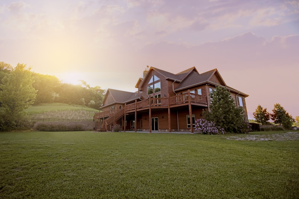 Casa de madera marrón con campo de hierba verde