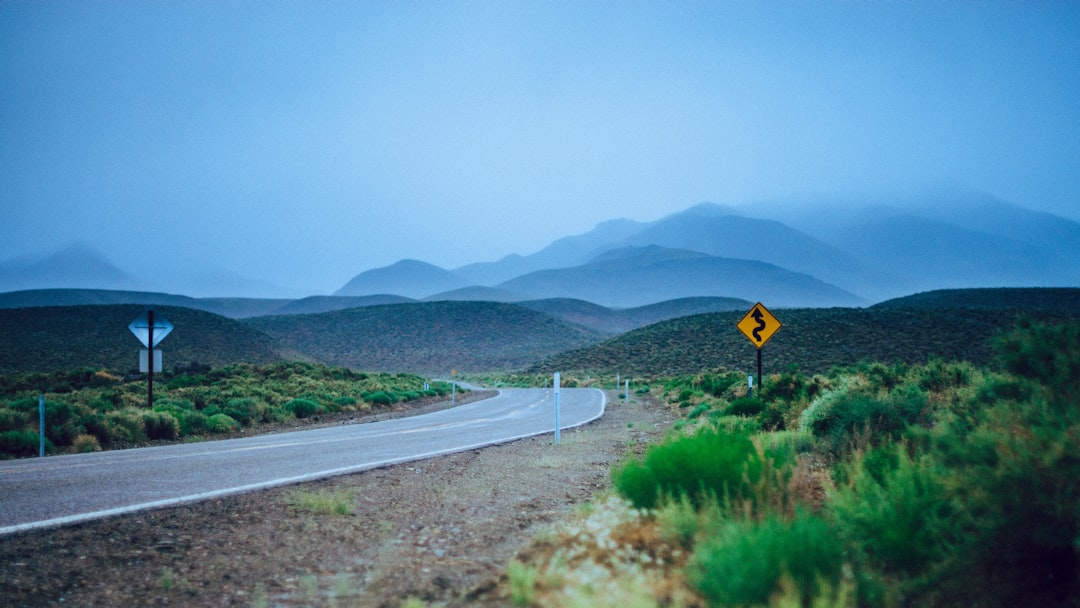 empty curve road near hills at daytime