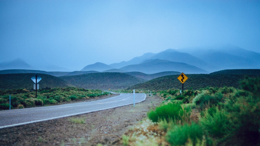 empty curve road near hills at daytime