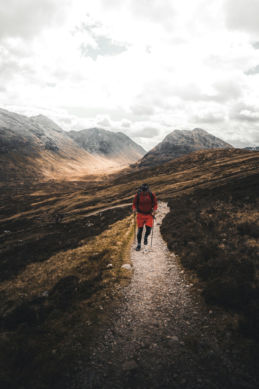 man walking on road under dramatic clouds