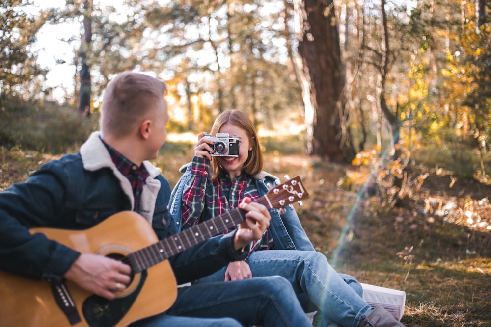 woman taking picture of man playing guitar