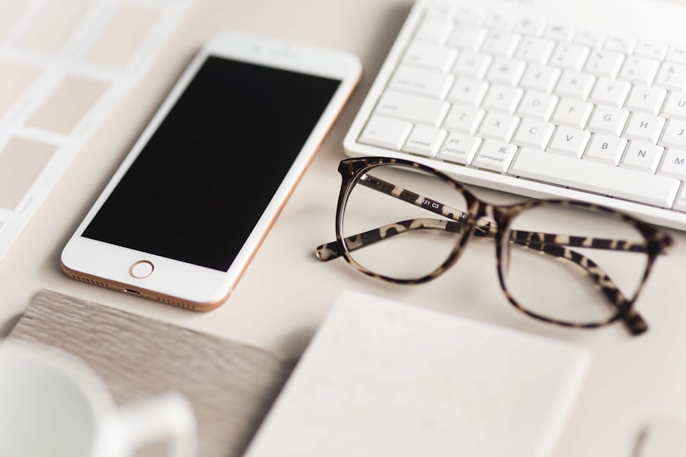 gold iPhone 7 beside black and brown framed eyeglasses