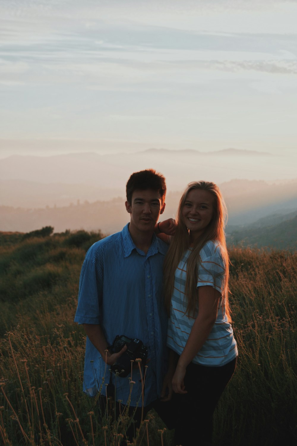 man wearing teal button-up shirt holding black DSLR camera