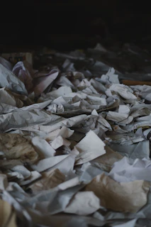 A chaotic scene of scattered documents and fake IDs under a harsh red light.