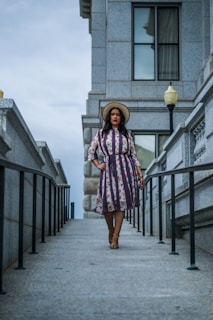 A vibrant street style shot featuring a woman in a flowing floral dress paired with ankle boots and a wide-brimmed hat.