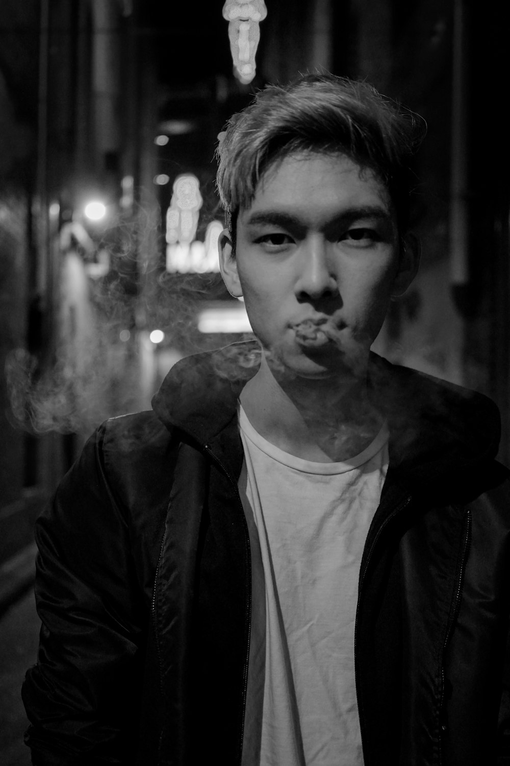 man in black jacket and white top smoking cigarette
