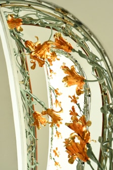 An ornate staircase railing is adorned with intricate floral designs featuring golden orange flowers and twisting green vines, creating an elegant and artistic display.