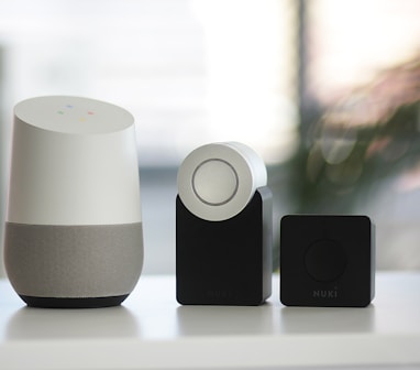 white and gray Google smart speaker and two black speakers
