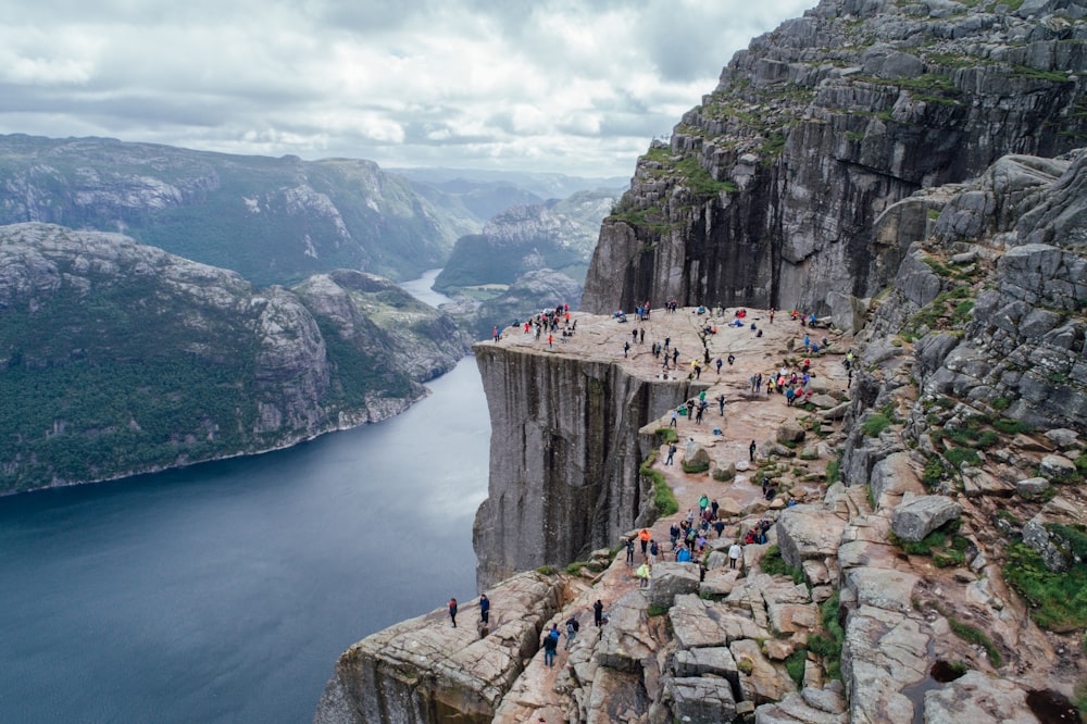 people gathering at the rock plateau overlooking the body of water below