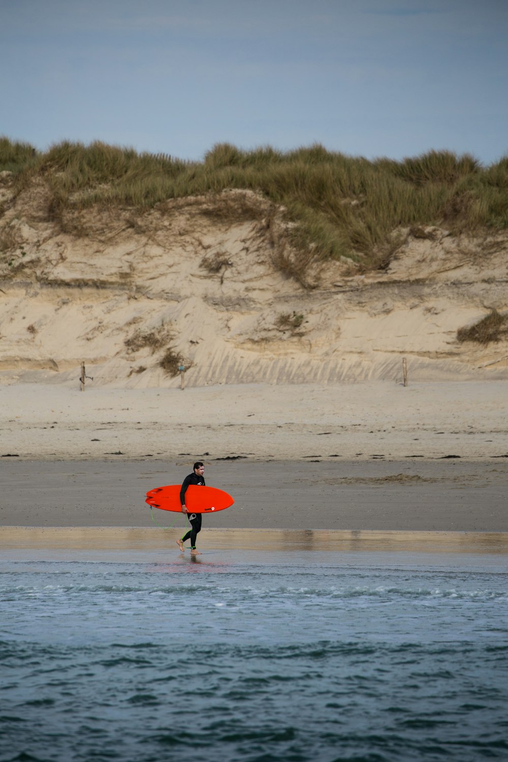 man carrying surfboard walking on seashore