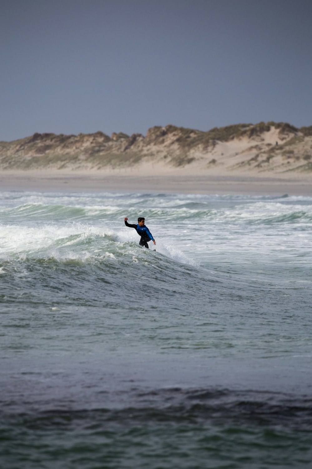 surfeur surfant sur les vagues sous un ciel gris
