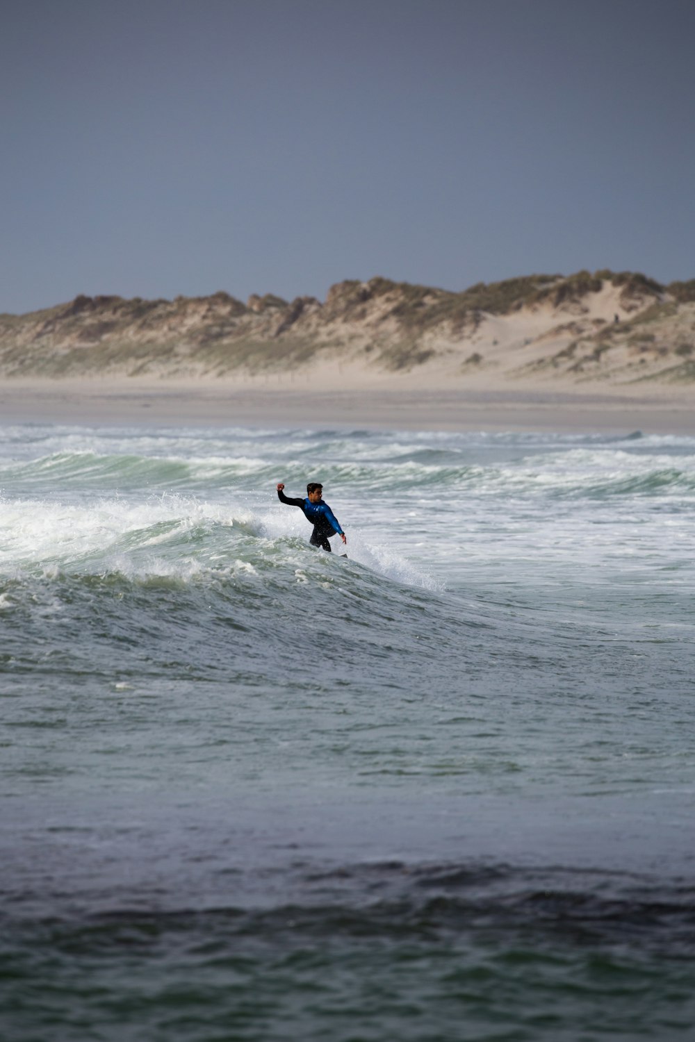 surfer riding the waves under grey sky