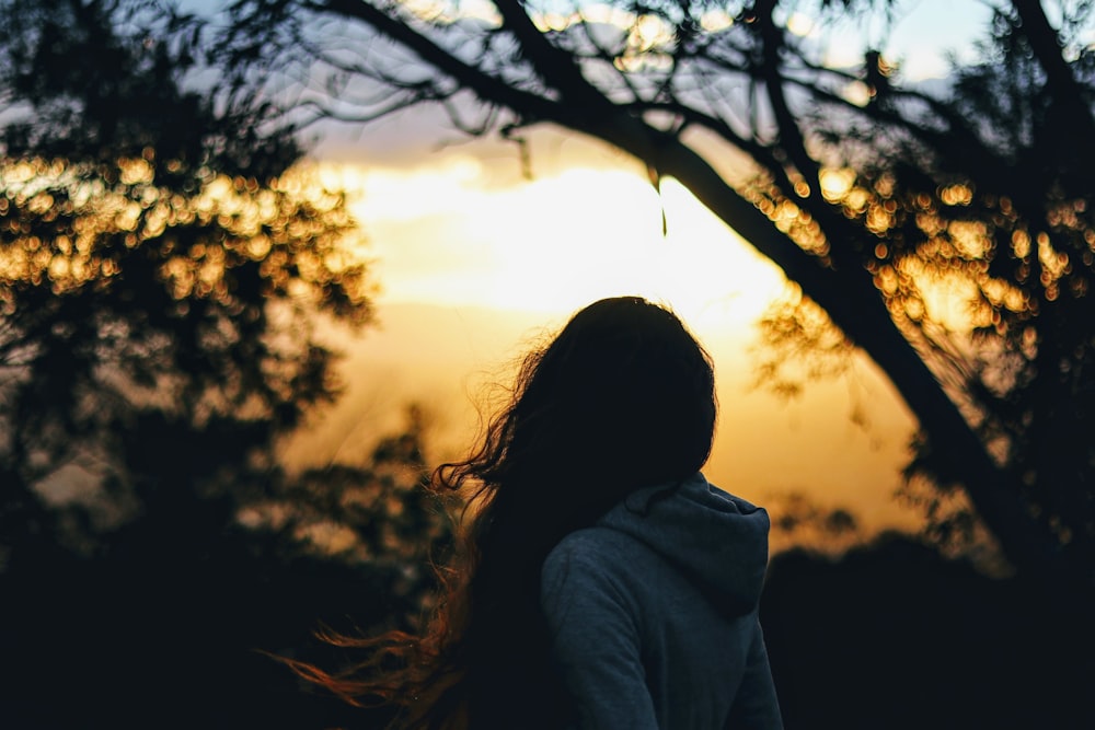 women stading beside a tree during golden hour