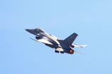 Close-up of a sleek fighter jet soaring against a clear blue sky.