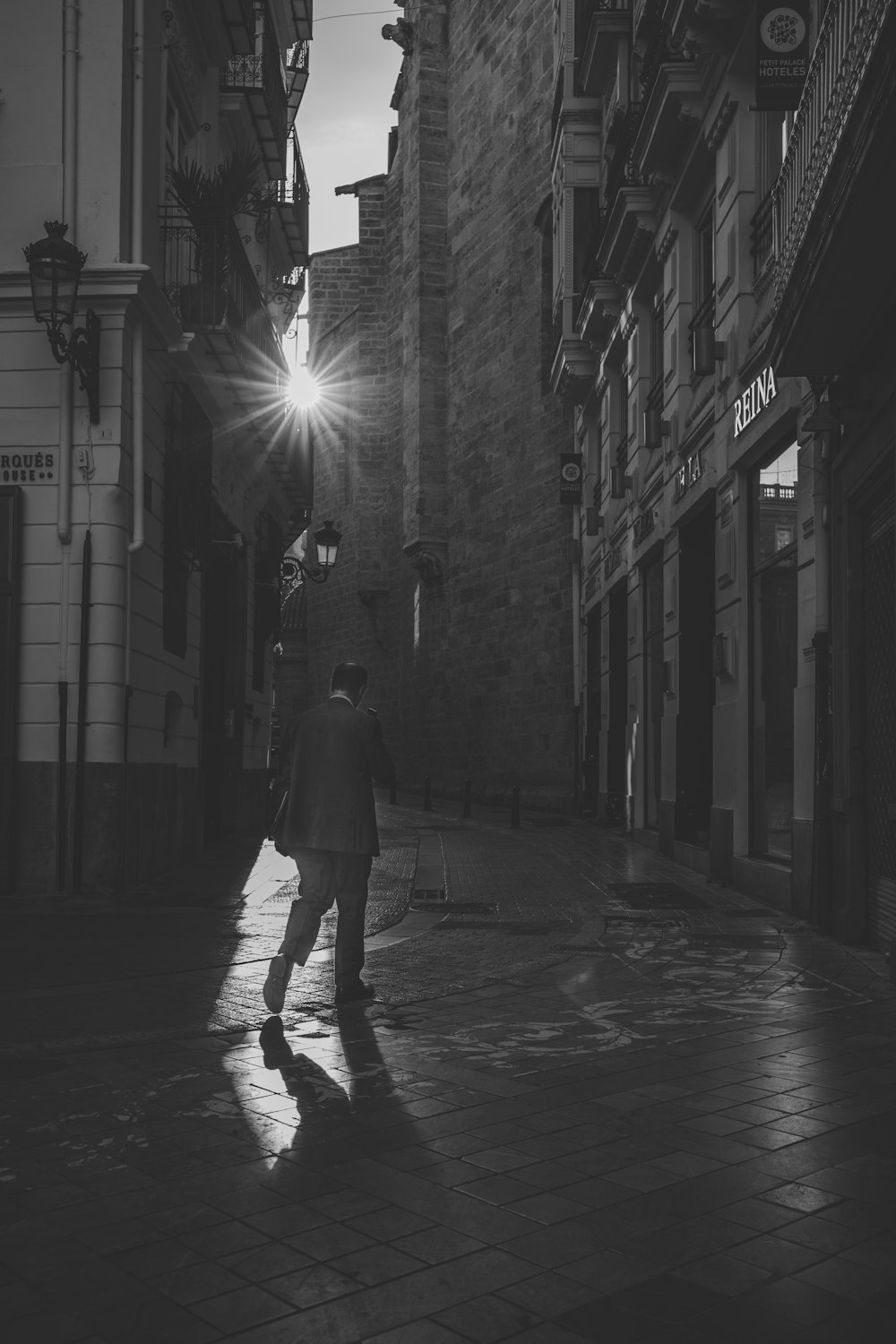 man walking on alley road grayscale photo