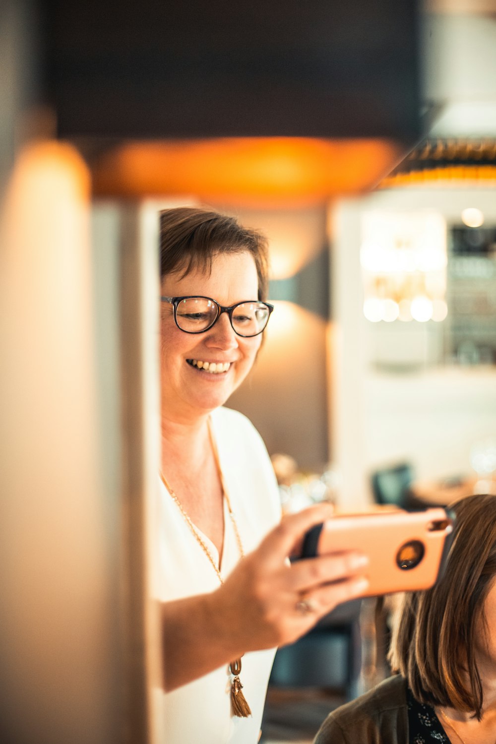 shallow focus photo of woman in white V-neck shirt using iPhone