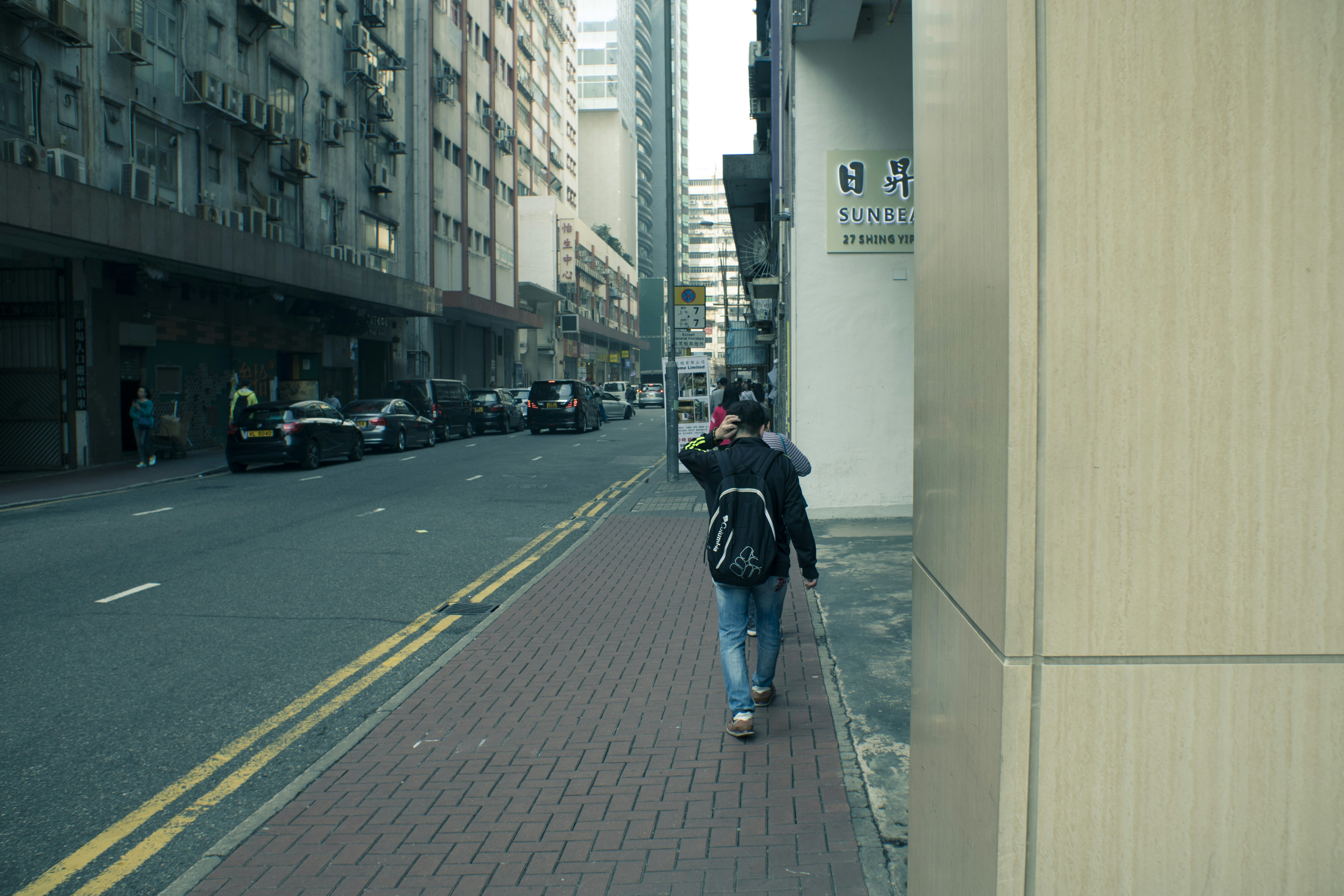 woman carrying backpack walking beside road