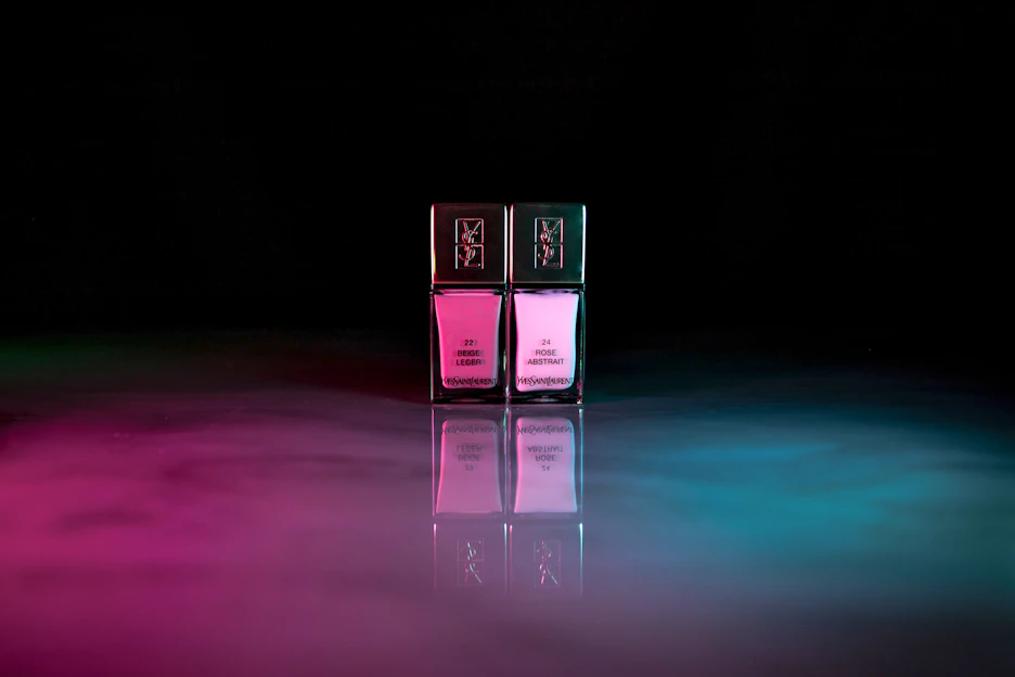 Close-up of glossy, richly pigmented gel nail polish bottles arranged neatly on a white surface with subtle light pink accents.