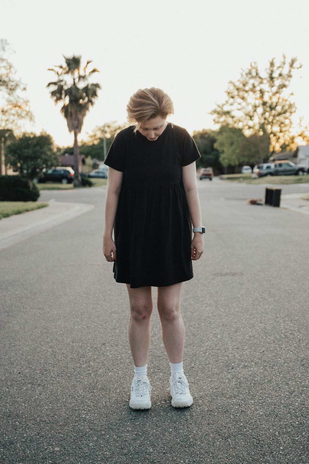 woman in black dress standing in the middle of road