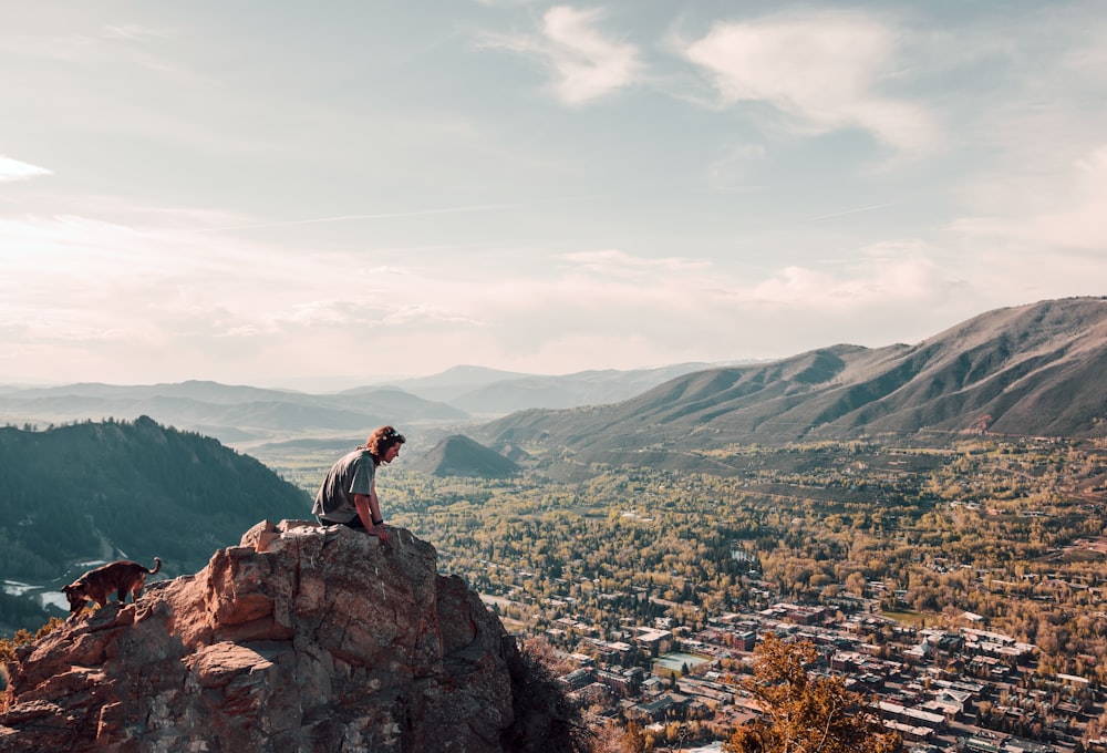 man wearing grey shirt sitting on cliff