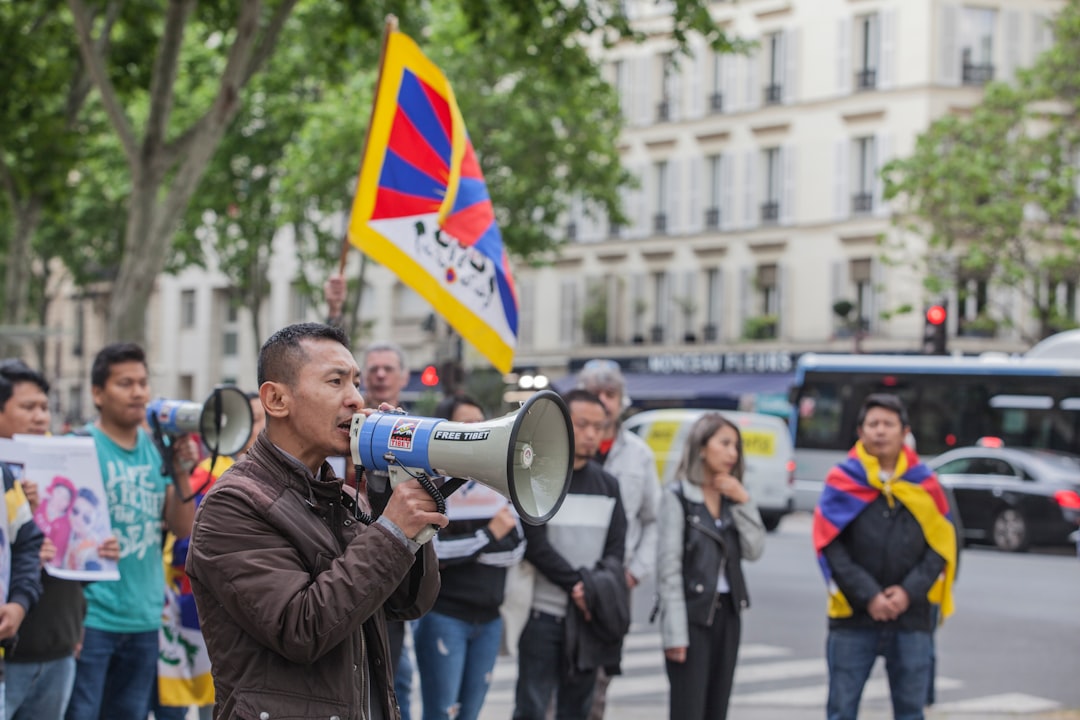 man in brown jacket using megaphone with protesters