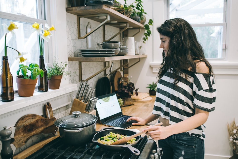 woman in black and white striped cold-shoulder t-shirt cooking