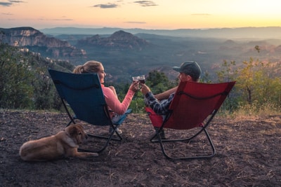 two person sitting on camping chairs while watching mountain