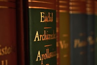 Close-up view of a row of books with green and brown spines, featuring gold lettering with names like Euclid, Archimedes, and Apollonius.