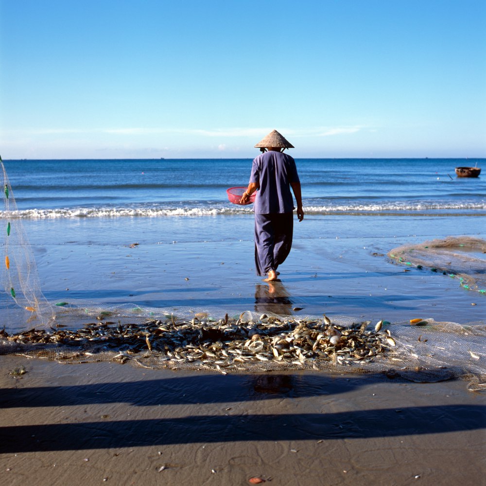 person holding basket walking towards the beach