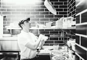 Chef tossing pizza dough in the air in a rustic kitchen setting.